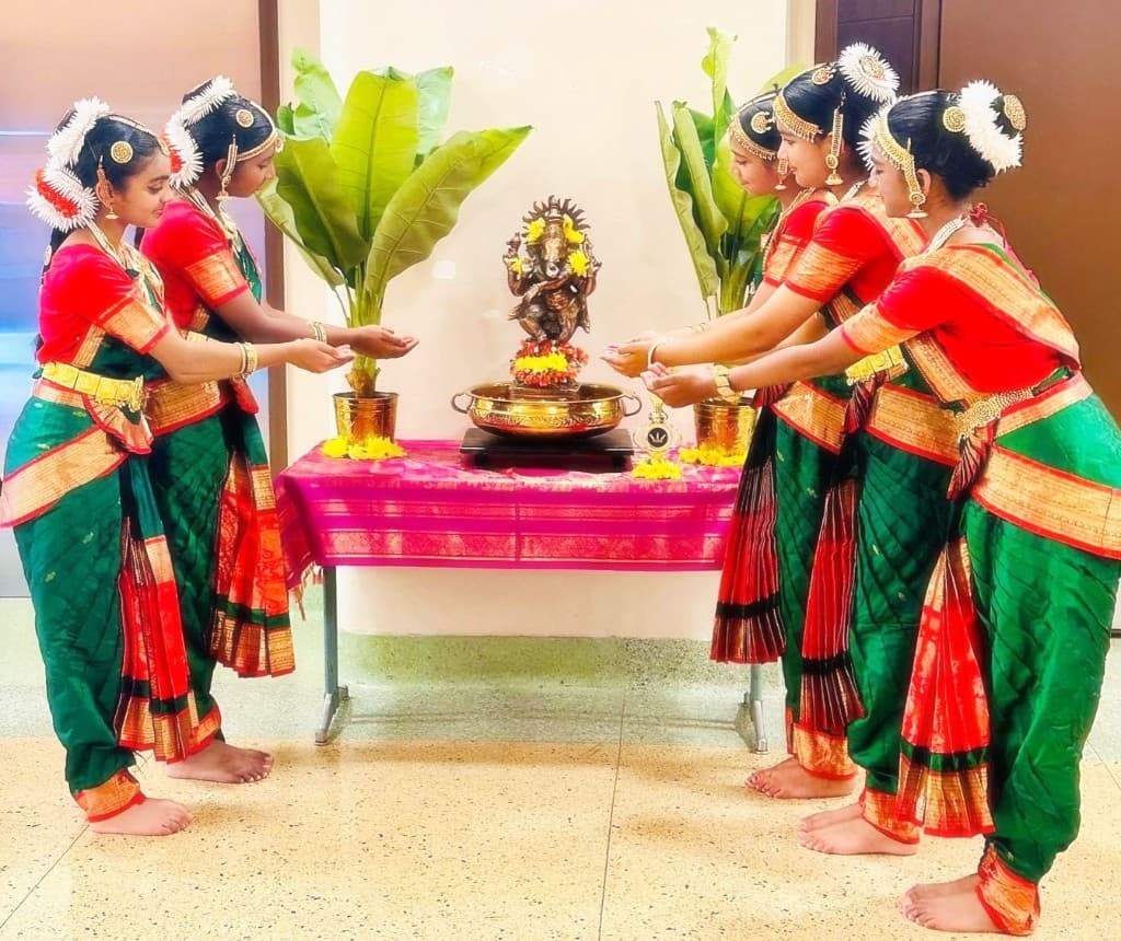 Classical dancers performing before a Ganesha altar
